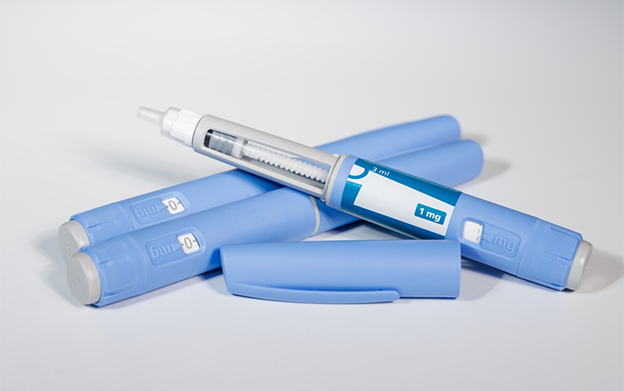 Blue insulin pen with its cap removed, showing the dose window on a white background.