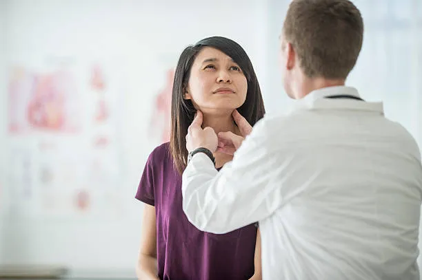 Doctor palpates a patient’s neck during a clinical throat examination in a clinic setting.
