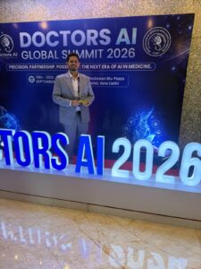 Man in a light gray suit holds a trophy on a blue Doctors AI Global Summit 2026 backdrop stage.