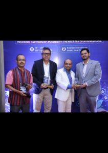 Four men in business attire pose with awards in front of a blue event backdrop at a conference.