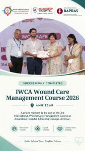 Group of four professionals on stage posing with a certificate at a medical course event, with logos and banner in the background.",