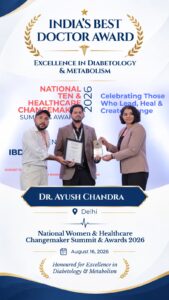 Three people on a stage presenting a plaque and trophy at an award ceremony; banner reads India's Best Doctor Award and Excellence in Diabetology & Metabolism.