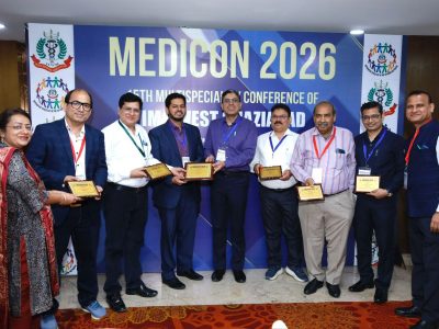 Group of ten professionals posing with award plaques at MEDICON 2026, with a blue conference banner in the background