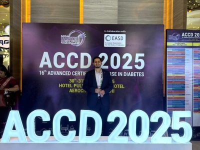 Man in a suit posing in front of a large ACCD 2025 banner at a hotel lobby conference venue.
